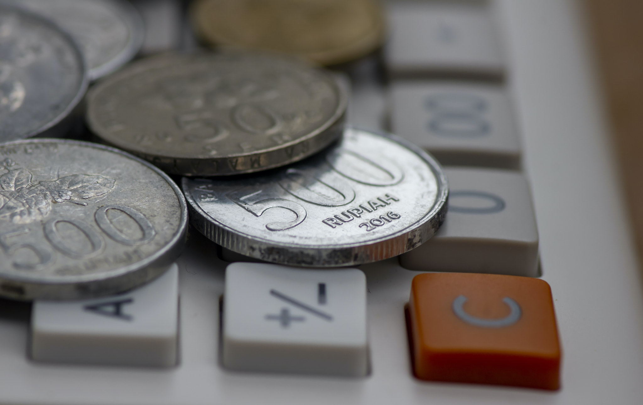 Close up of old Indonesian money rupiah coins on a calculator button, selected focus