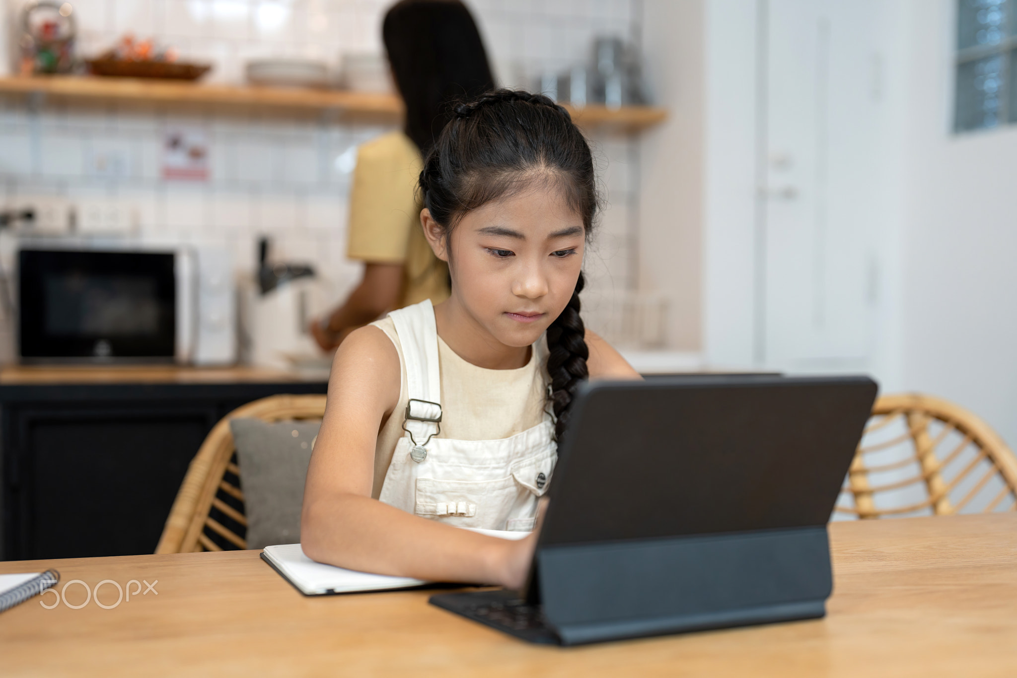 Portrait of little girl using laptop during online class with tutor or