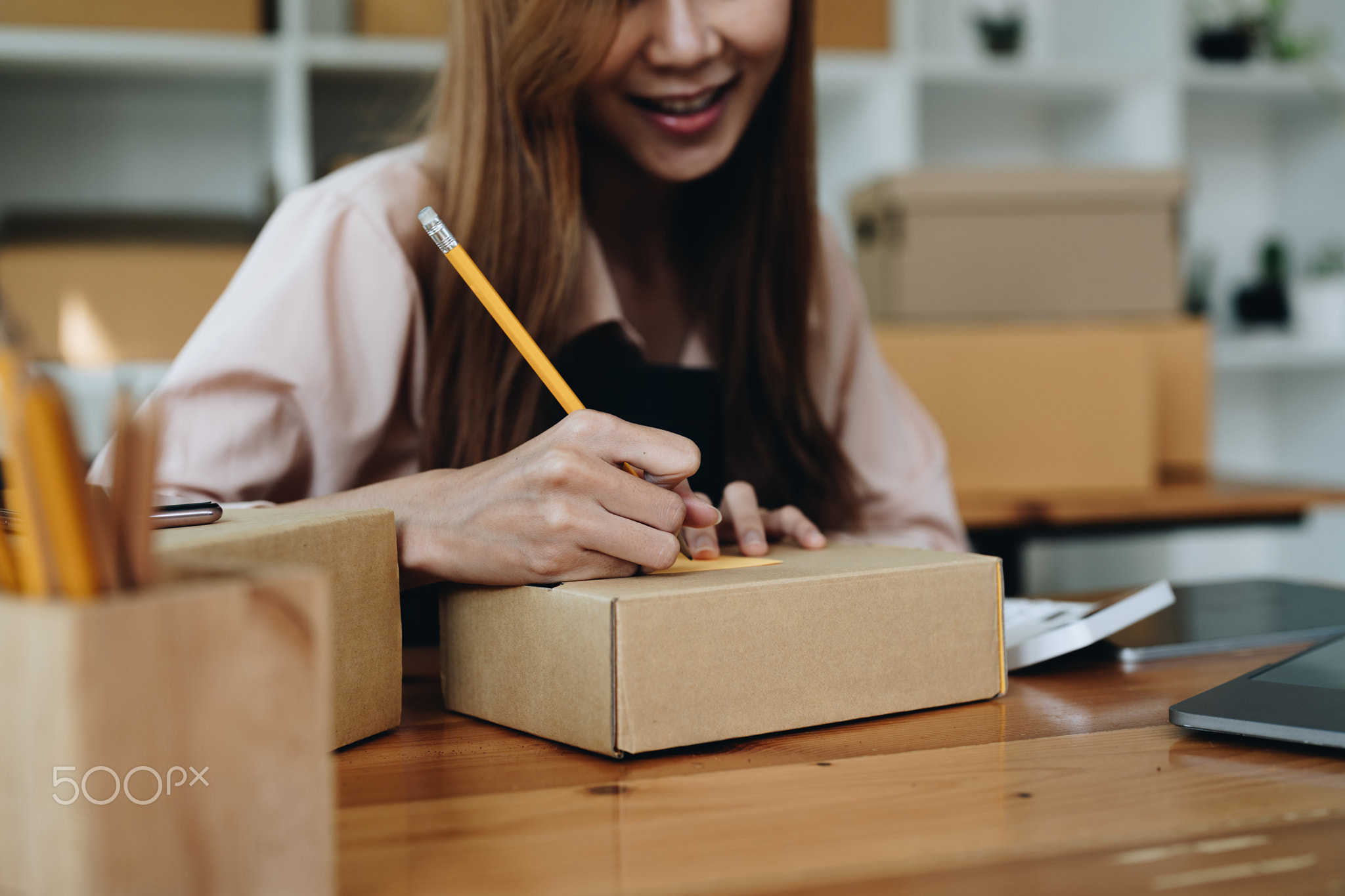 Happy young start up small business owner packing writing address on