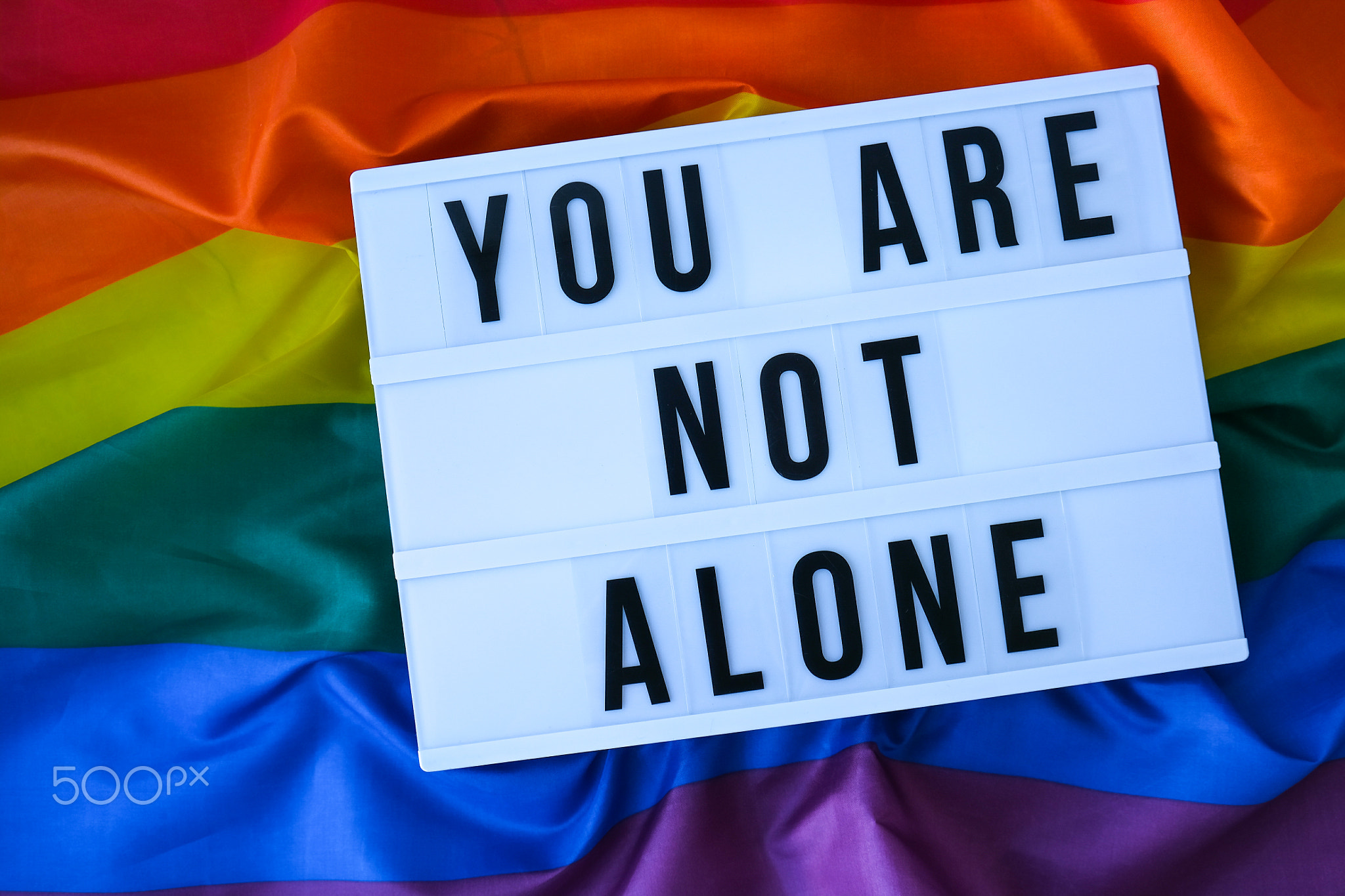 Rainbow flag with lightbox and text YOU ARE NOT ALONE. Rainbow lgbtq