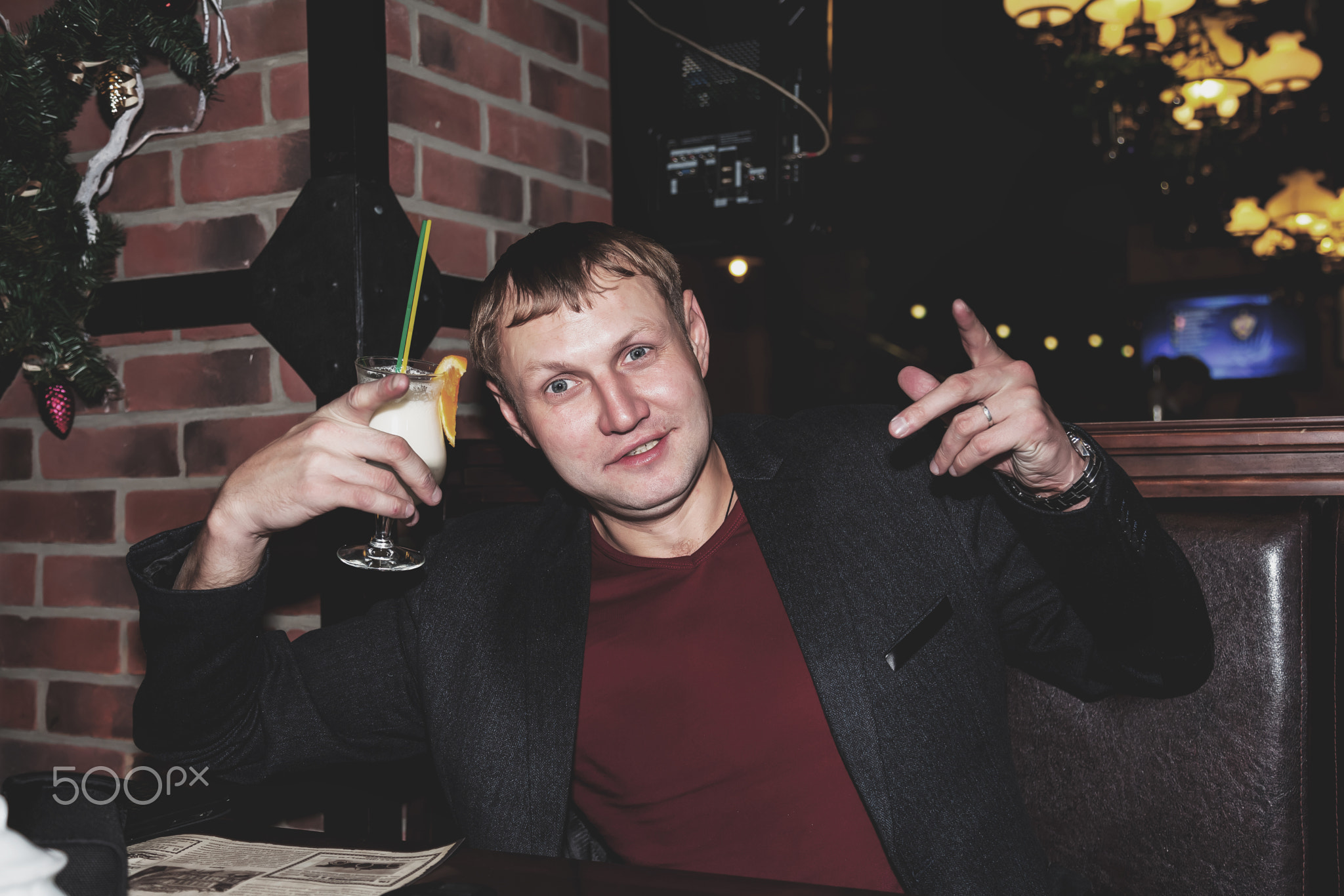 Handsome young man drinking cocktail in night bar at table