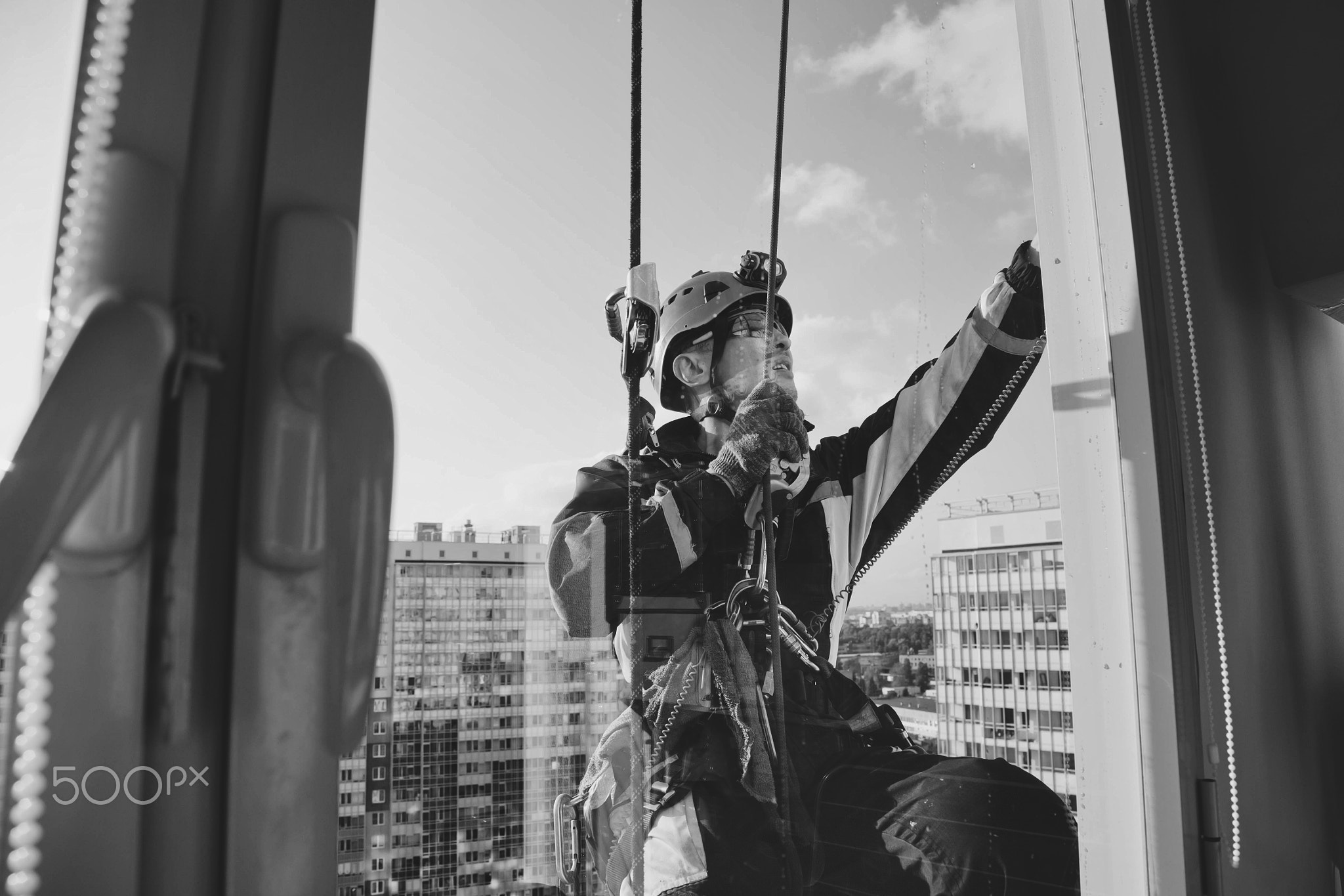 Industrial mountaineering worker hangs over residential facade building