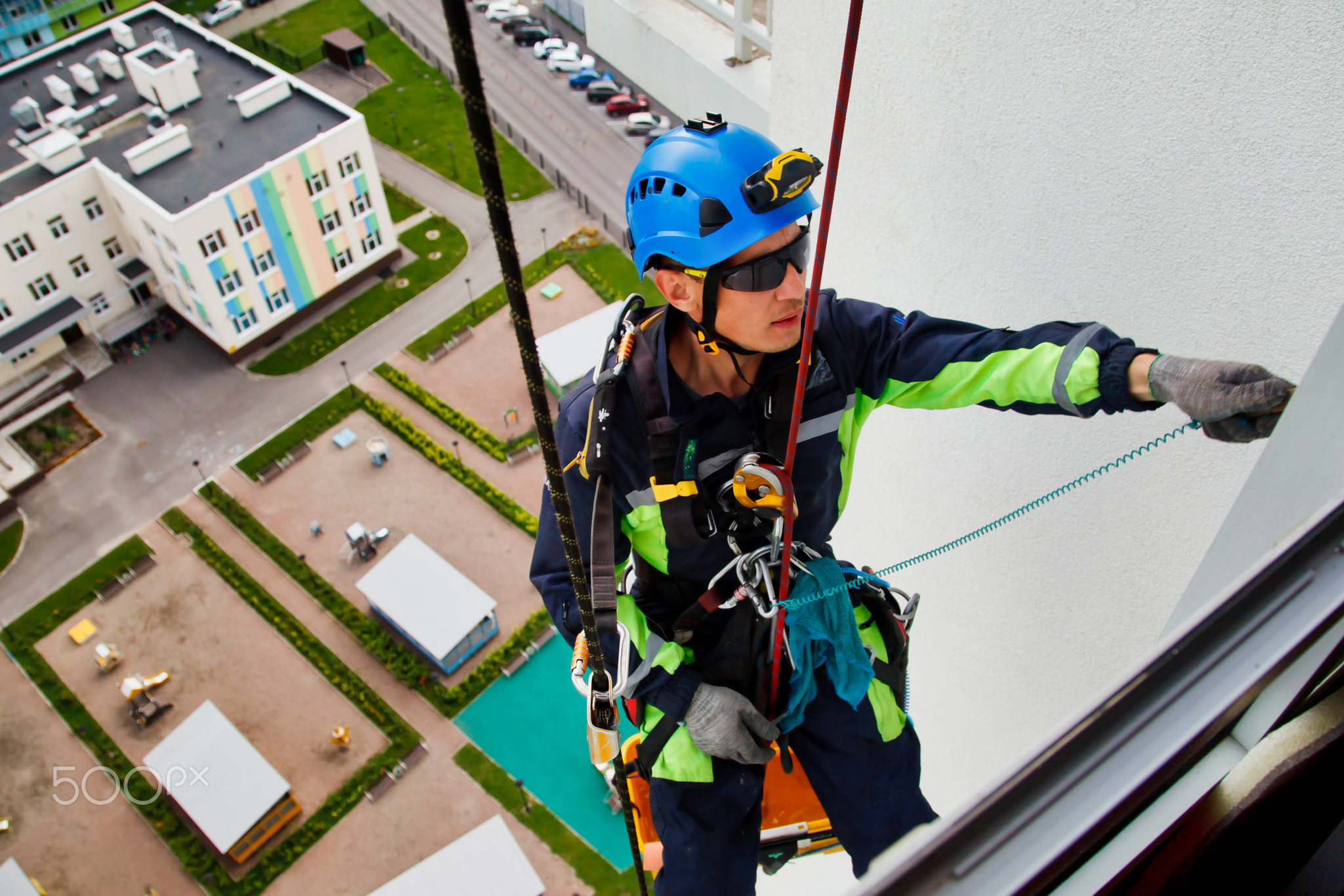 Industrial mountaineering worker hangs over residential facade building