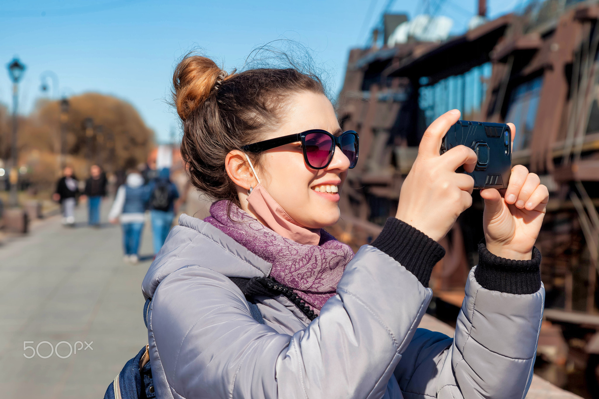 Portrait young tourist woman with phone, stands and takes photos of sights