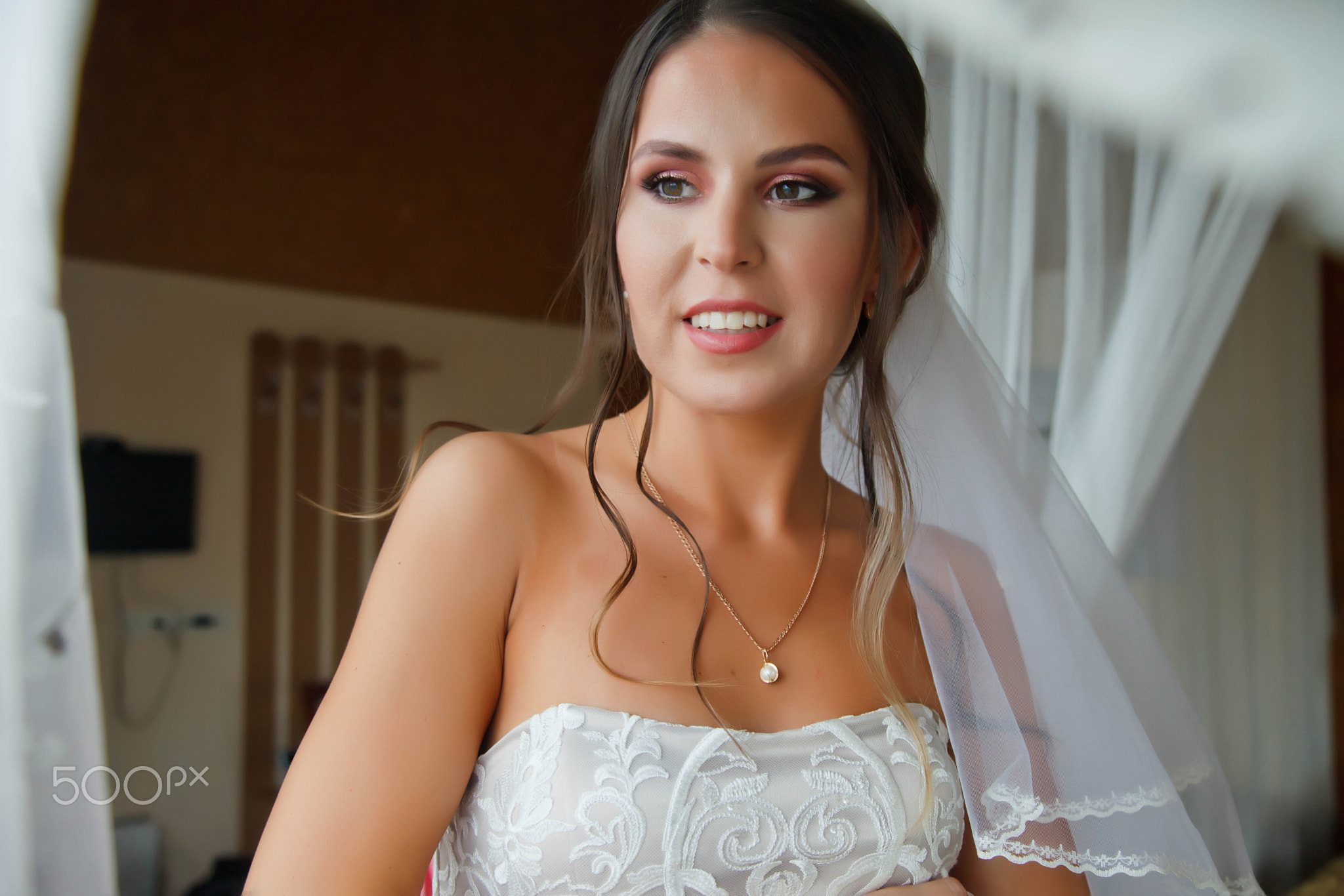 Cute young woman bride in home white dress at window in country house