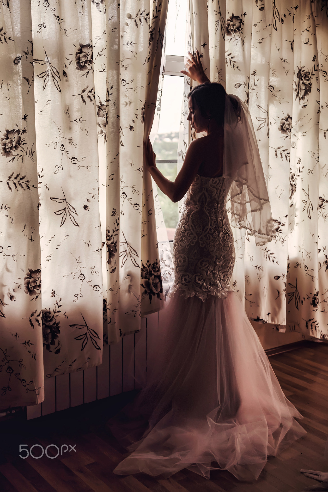 Cute young woman bride in home white dress at window in country house