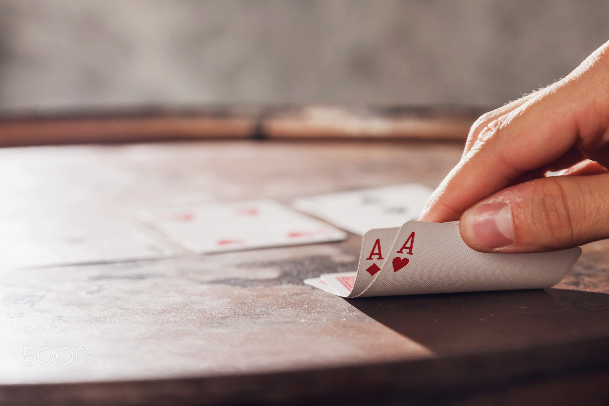 Close-up of mans hand showing his cards with two aces while playing poker on barrel