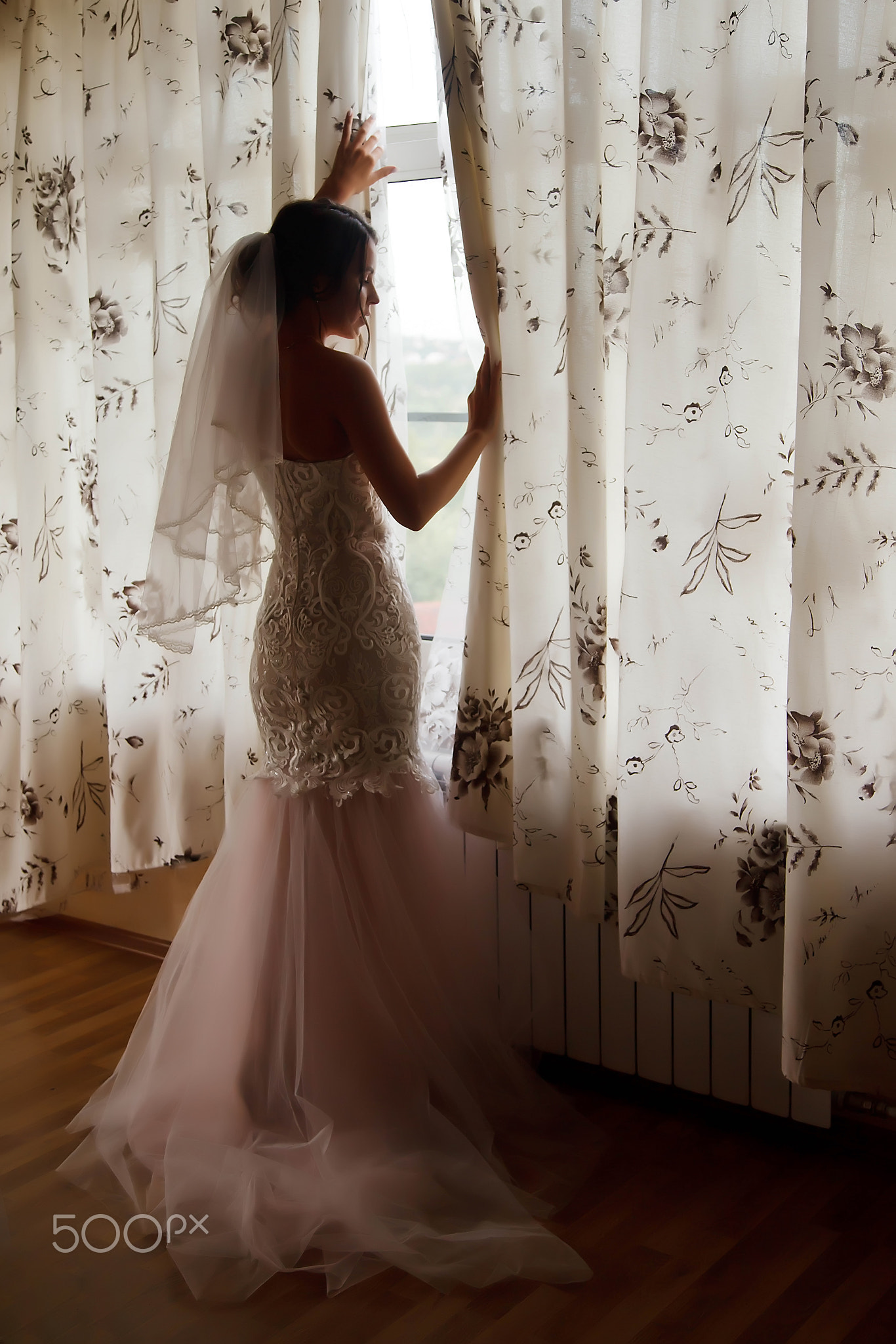 Cute young woman bride in home white dress at window in country house