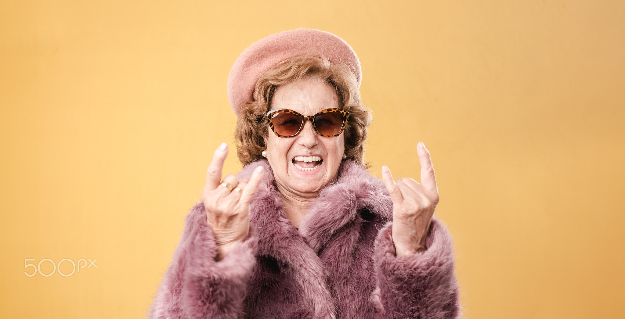 Stylish elderly woman showing rock and roll gesture