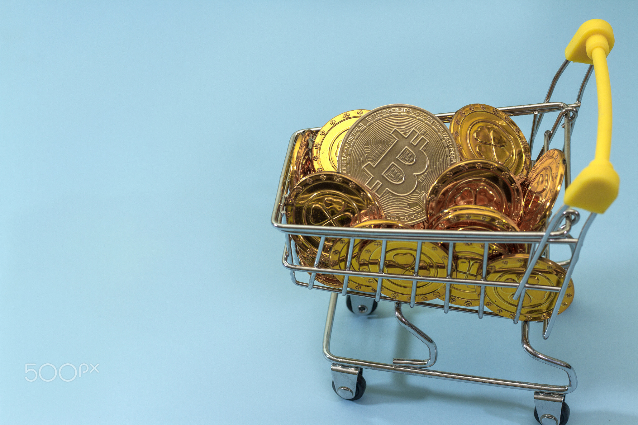 Bitcoin in shopping trolley on blue background, cryptocurrency