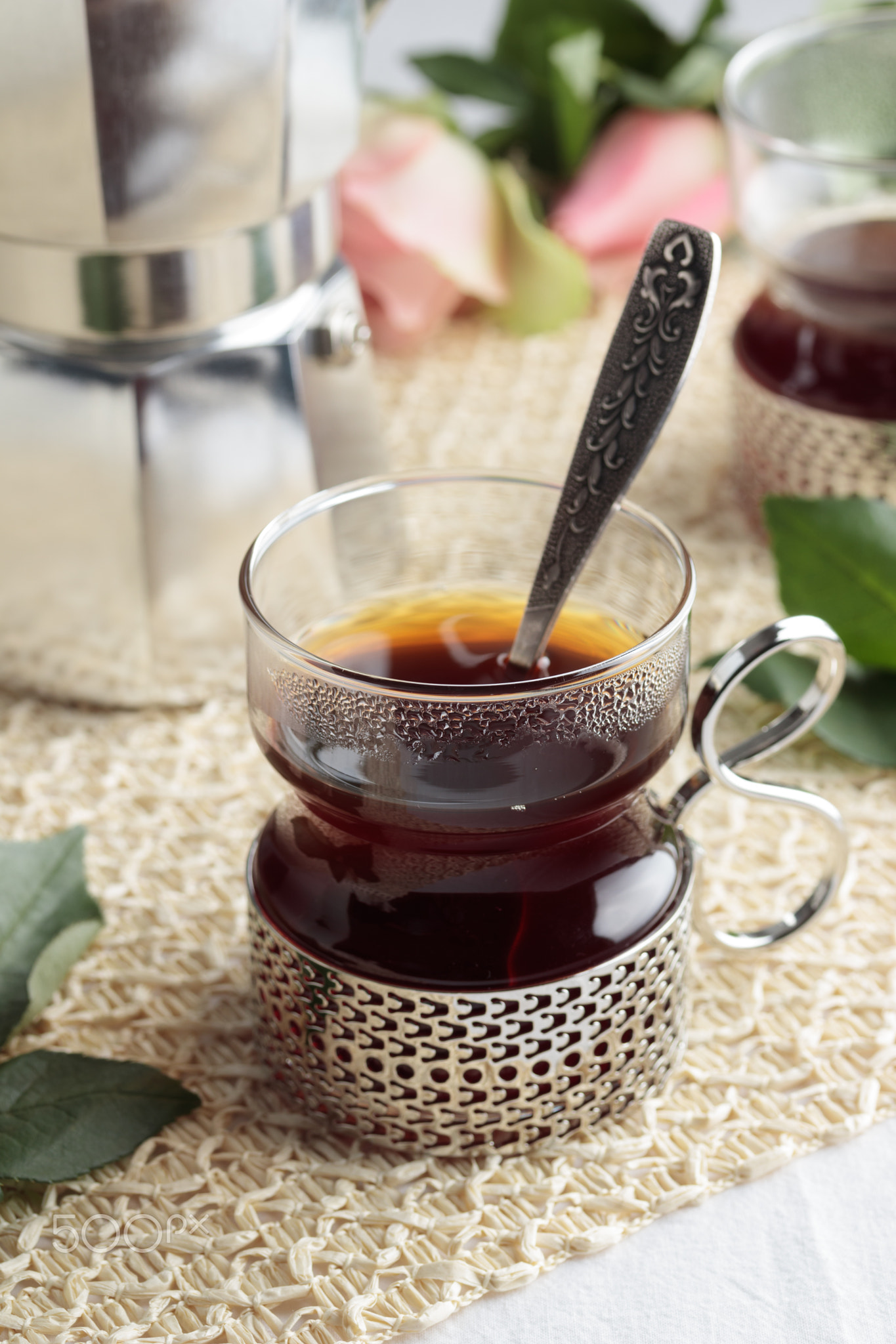 Cup of fresh coffee and coffee maker on white table