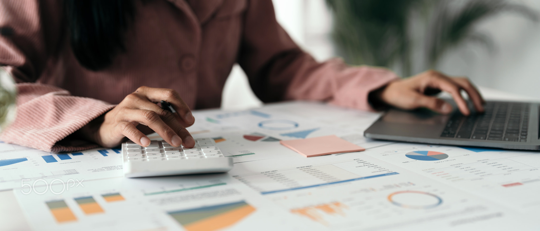 Close up hand of woman using computer calculating household finances
