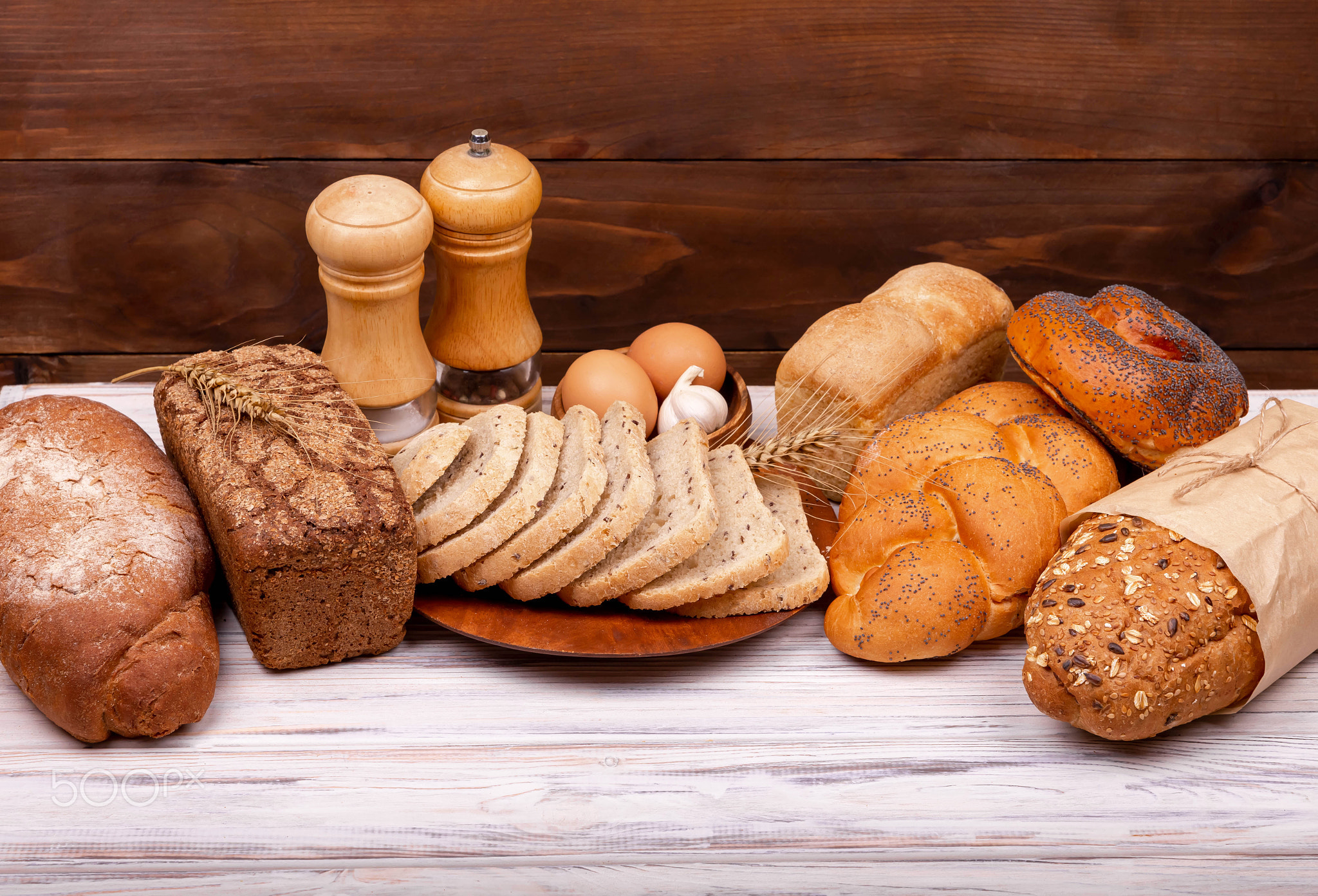 Assortment of tasty baked bread on dark and white background .