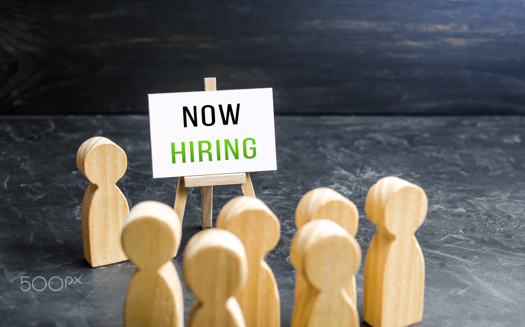 A man with a Now Hiring sign appeals to the crowd about hiring.