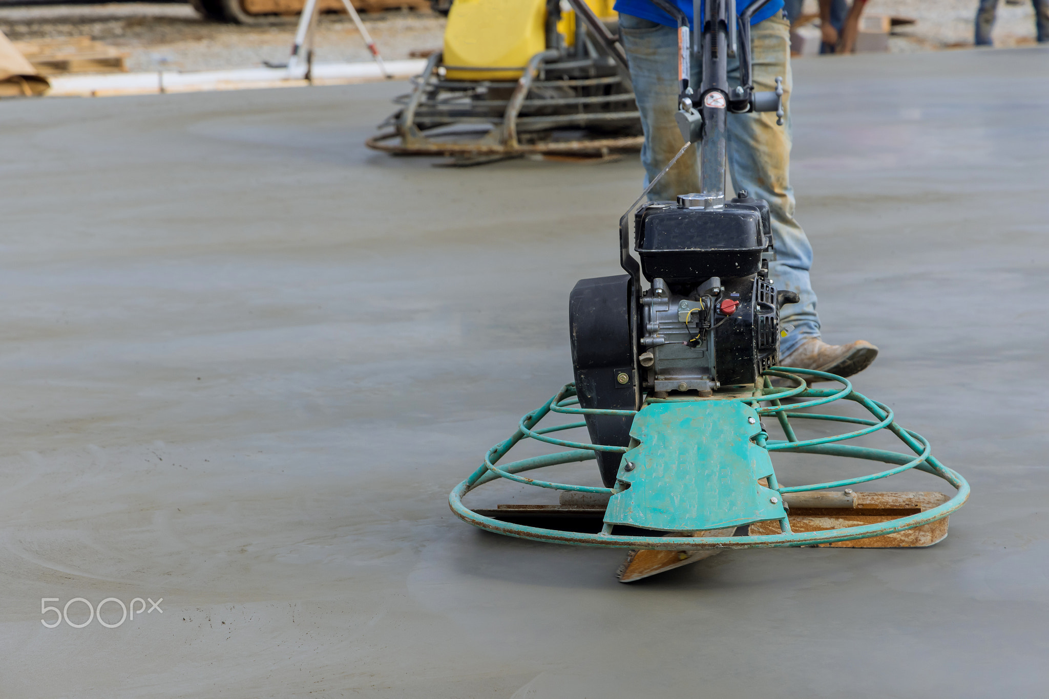 Laborer performing polishing cement screed foundation on the