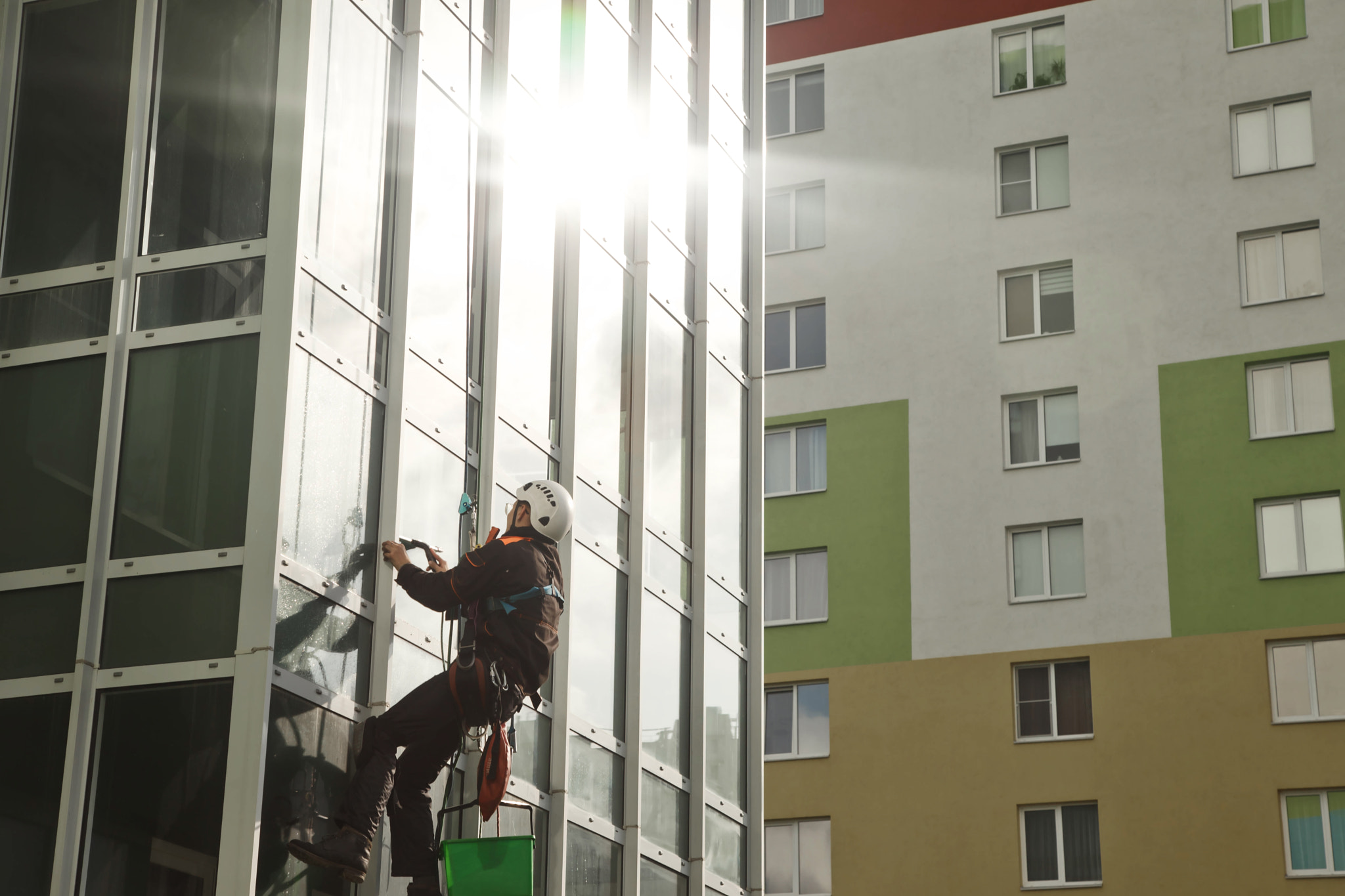 Concept of industry urban works. Industrial mountaineering worker in uniform hangs