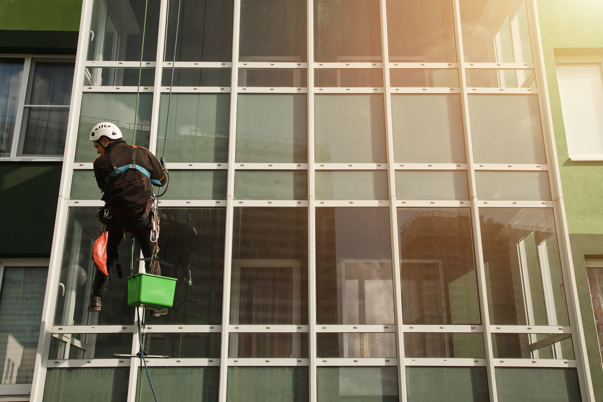 Concept of industry urban works. Industrial mountaineering worker in uniform hangs over building