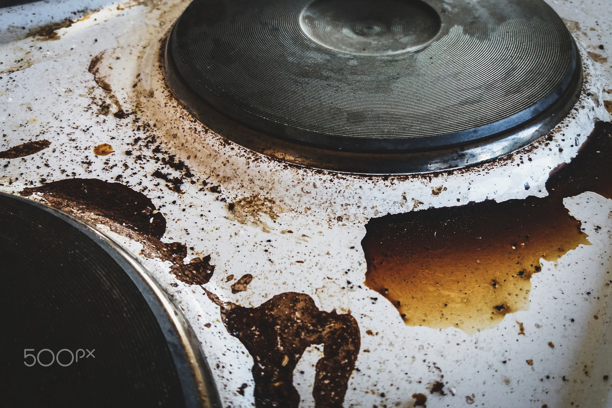 Dirty electric stove with burnt coffee stains, messy kitchen