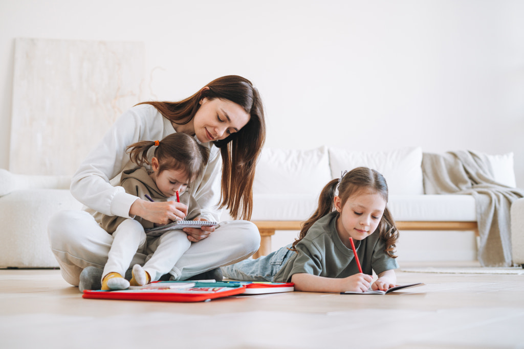 Preschool little girls sisters with mother drawing on floor at the bright room at home by Galina Zhigalova on 500px.com