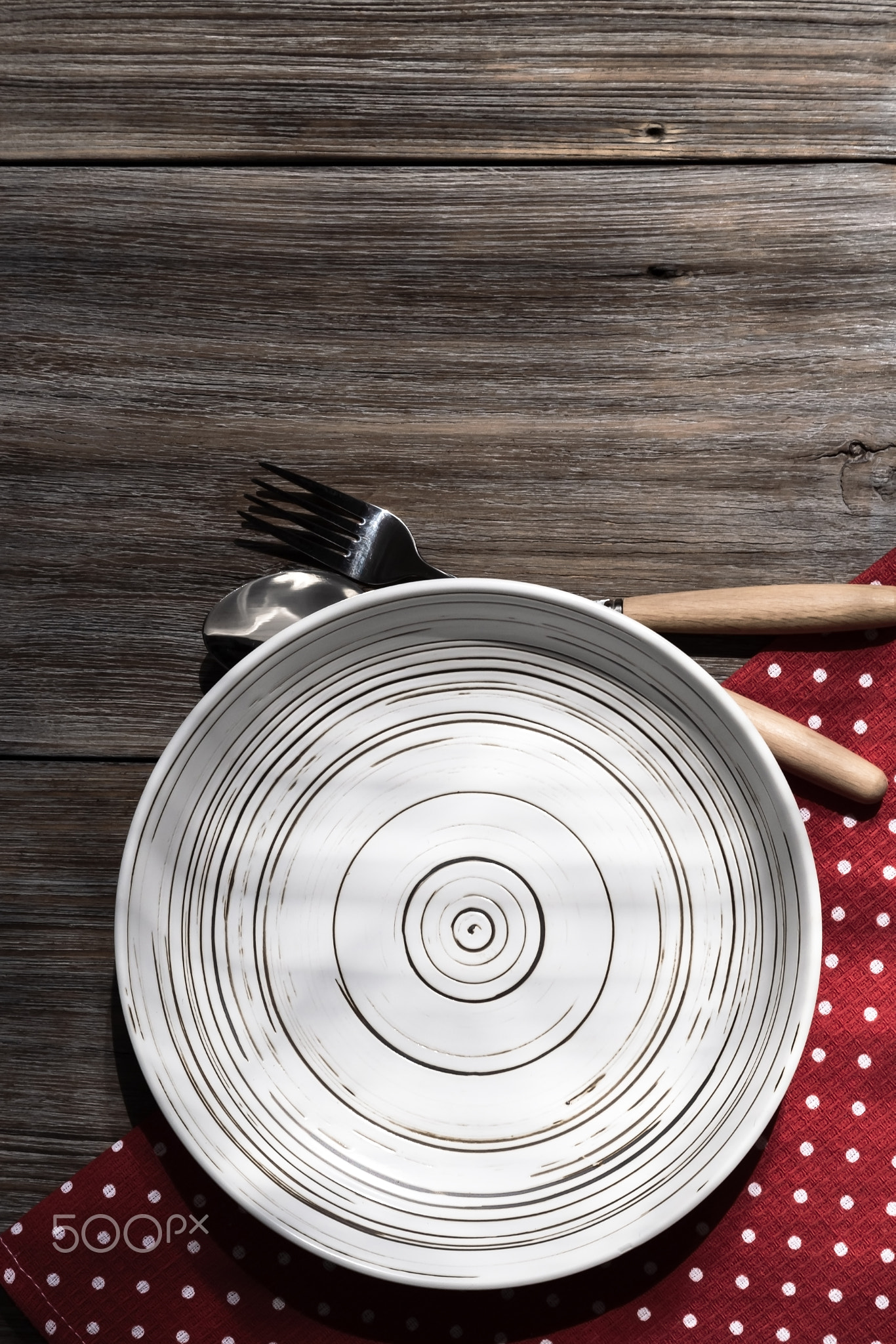 Empty ceramic white plate on a rustic loft wooden table. Kitchen food background