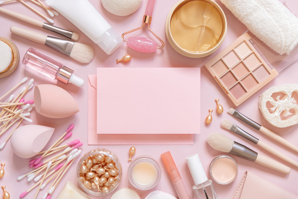 Paper card between skin care and decorative cosmetics on pink, top view, mockup by Ekaterina Fedotova on 500px.com