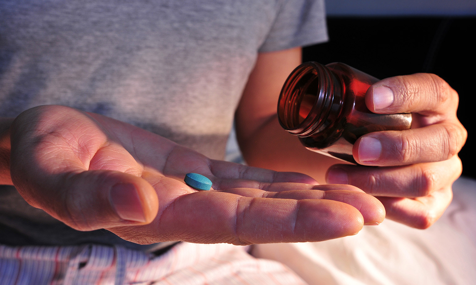 closeup-man-tipping-pill-bottle-pill-on-palm