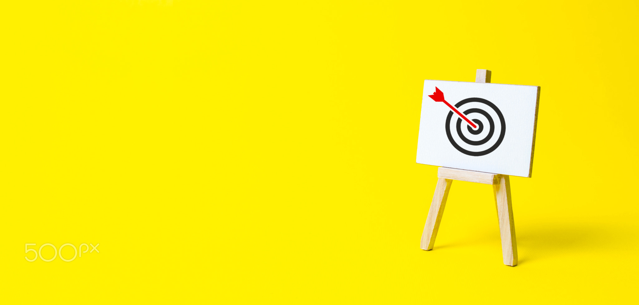 Sign stand with an arrow in the target on a yellow background.