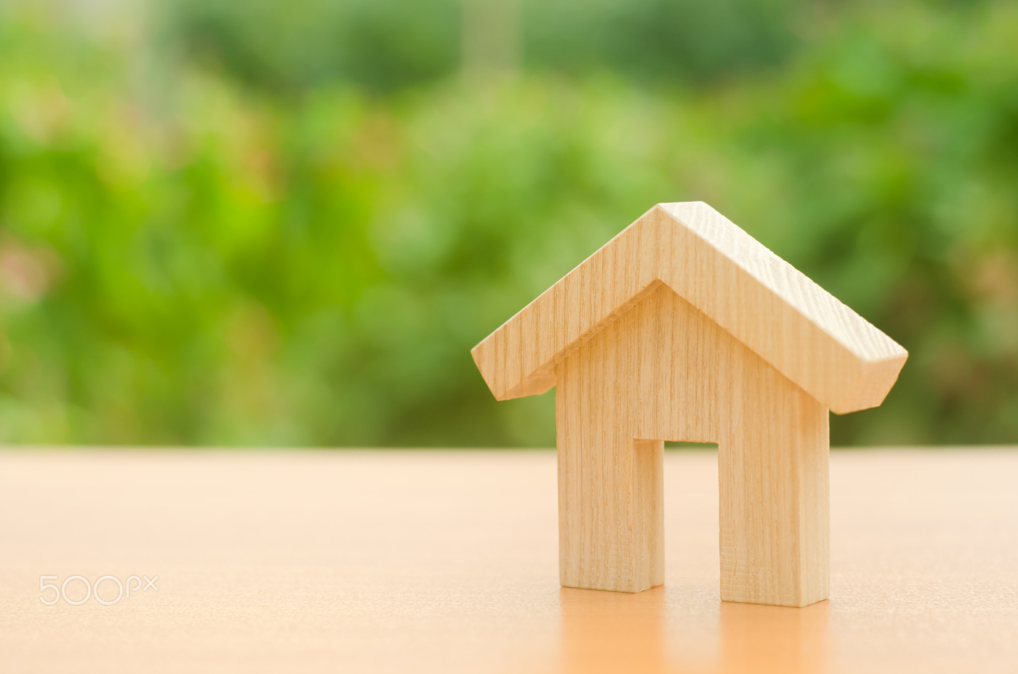 A wooden house stands on a nature green background.