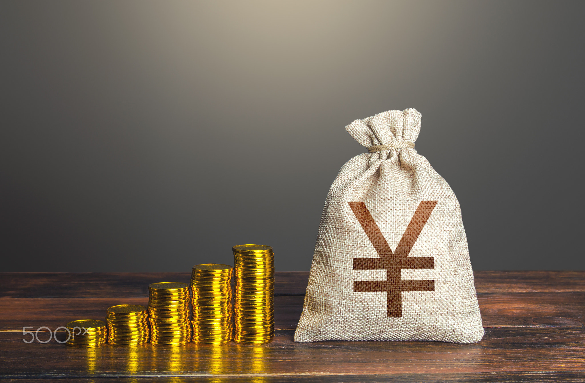 Chinese yuan or japanese yen money bag and increasing stacks of coins.