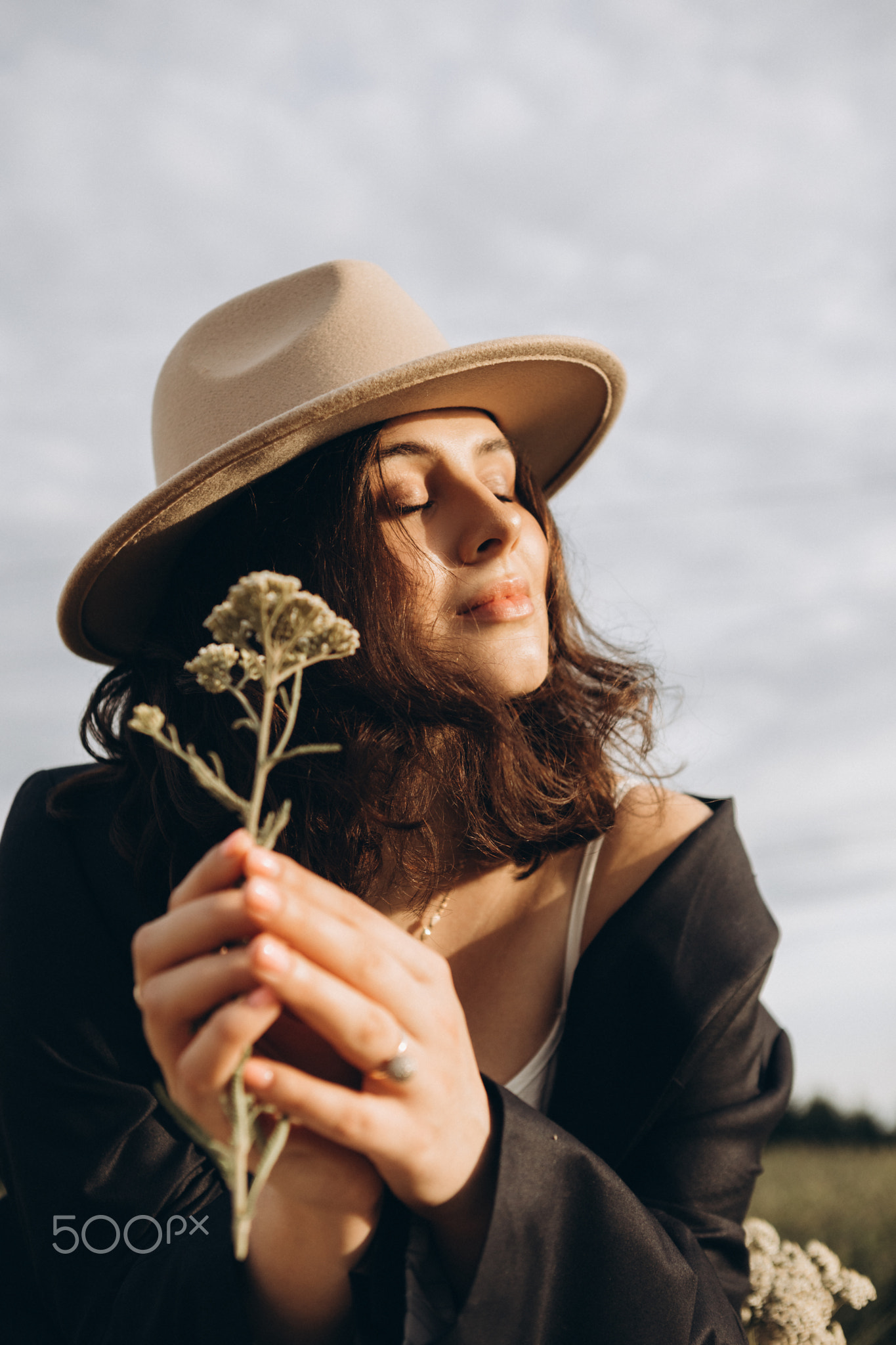 stylish young brunette girl in a beige hat and black shirt