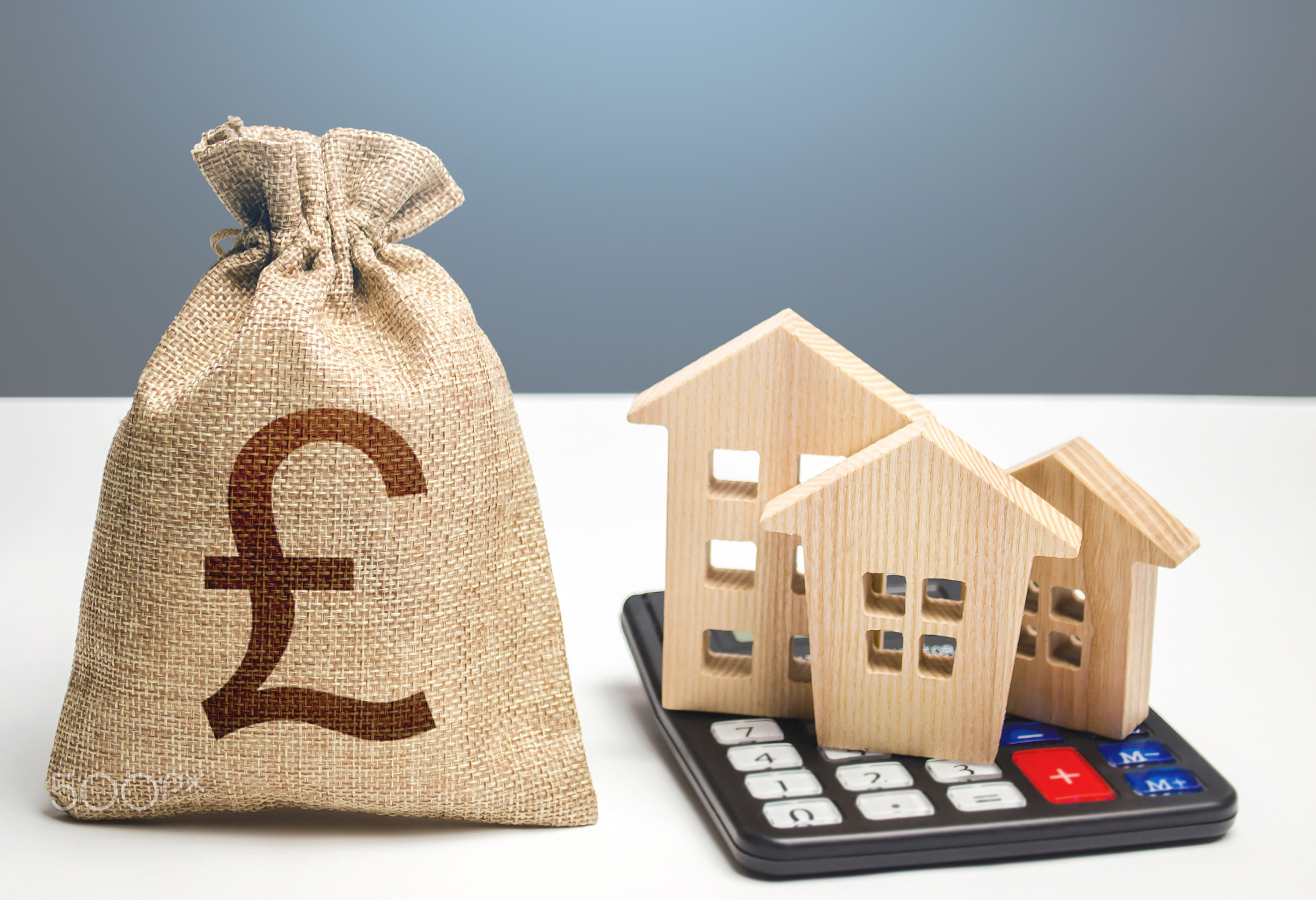 Houses on a calculator and british pound sterling money bag. Buying and selling