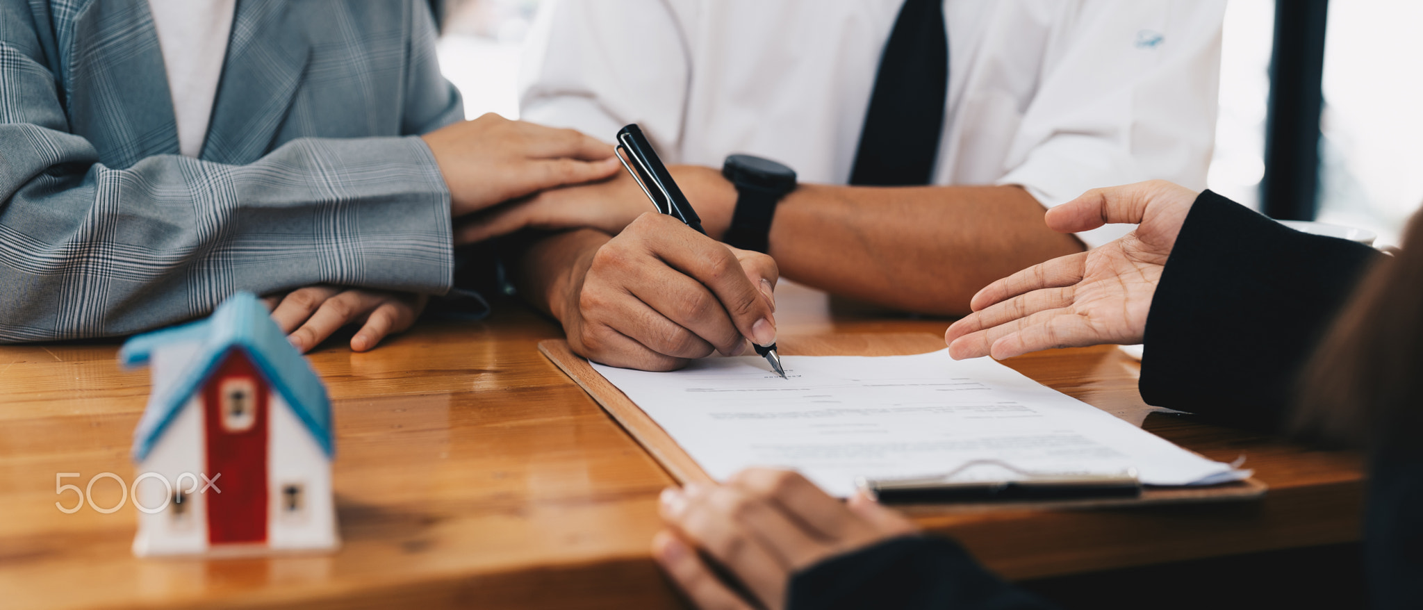 Business woman and young couple signing agreement for buying house