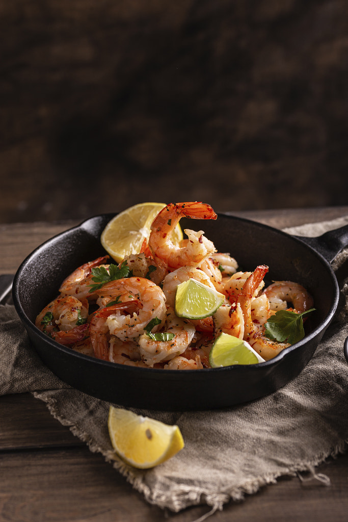 Grilled shrimps with greens and garlic in a pan by tmedvedtskaya / 500px