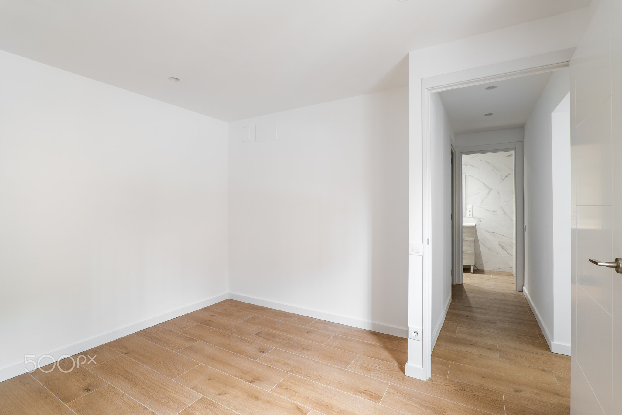 Empty room with laminate flooring and newly painted white wall in