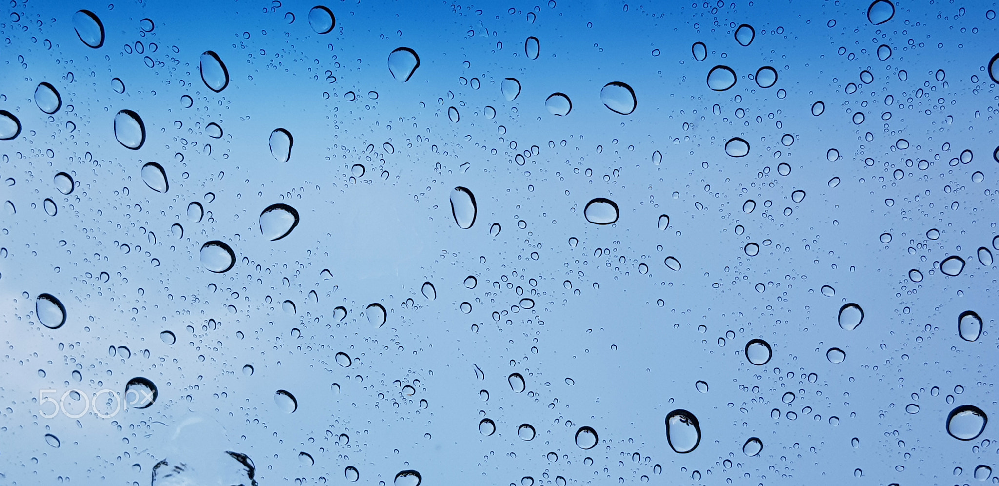 Water droplets perspective through window glass surface against blue sky good for multimedia content