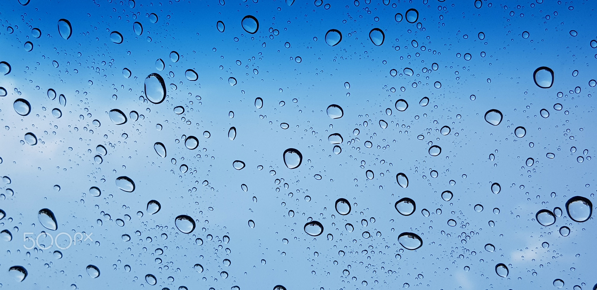 Water droplets perspective through window glass surface against blue sky good for multimedia content