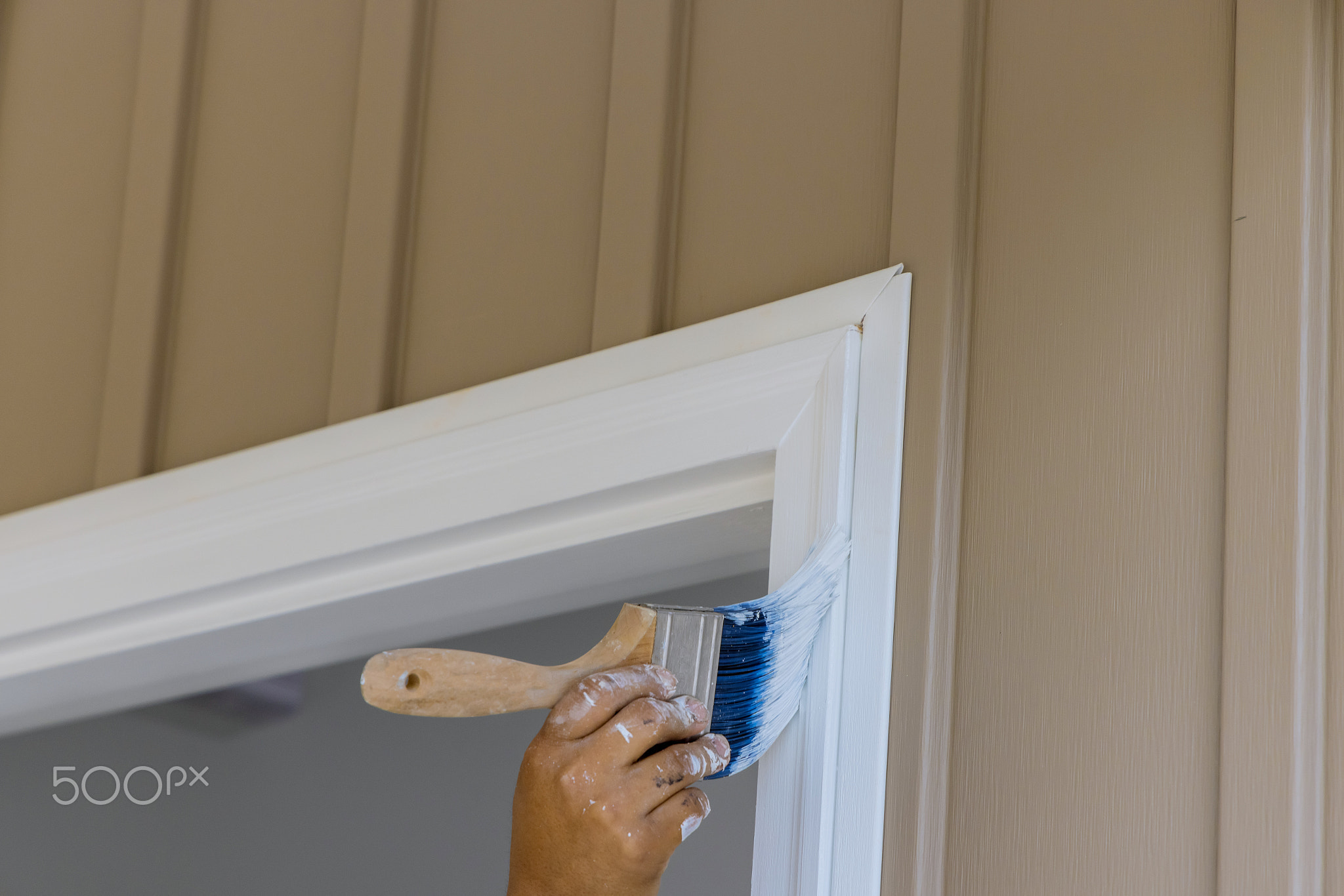 Using a paintbrush, a carpenter works on painting wooden moldings and