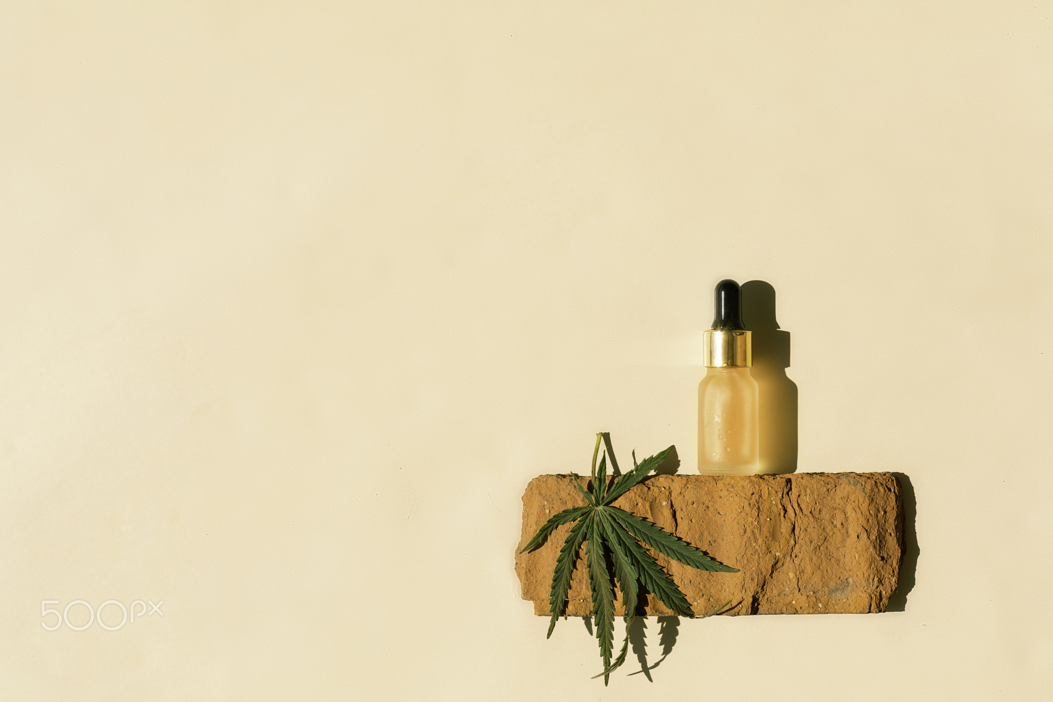 glass bottle with CBD oil, THC tincture and hemp leaves on a pastel