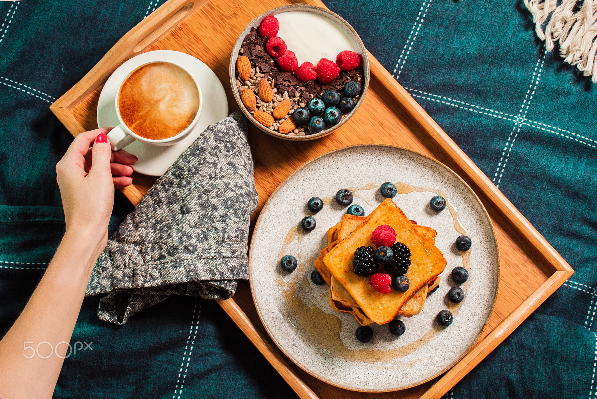 Breakfast in bed. Woman hand, yogurt bowl with berries, french toasts
