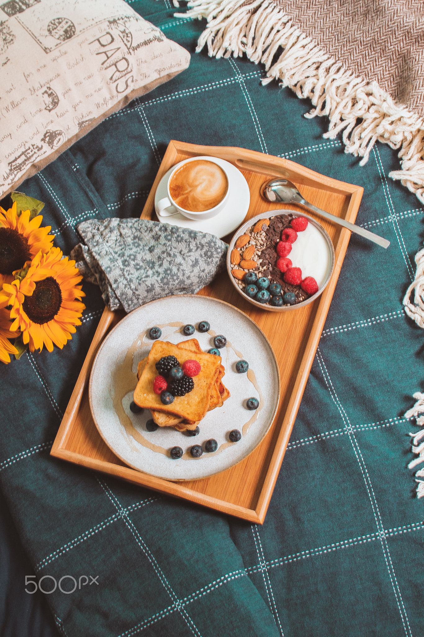 Cozy breakfast in bed from above, yogurt bowl with berries and nuts