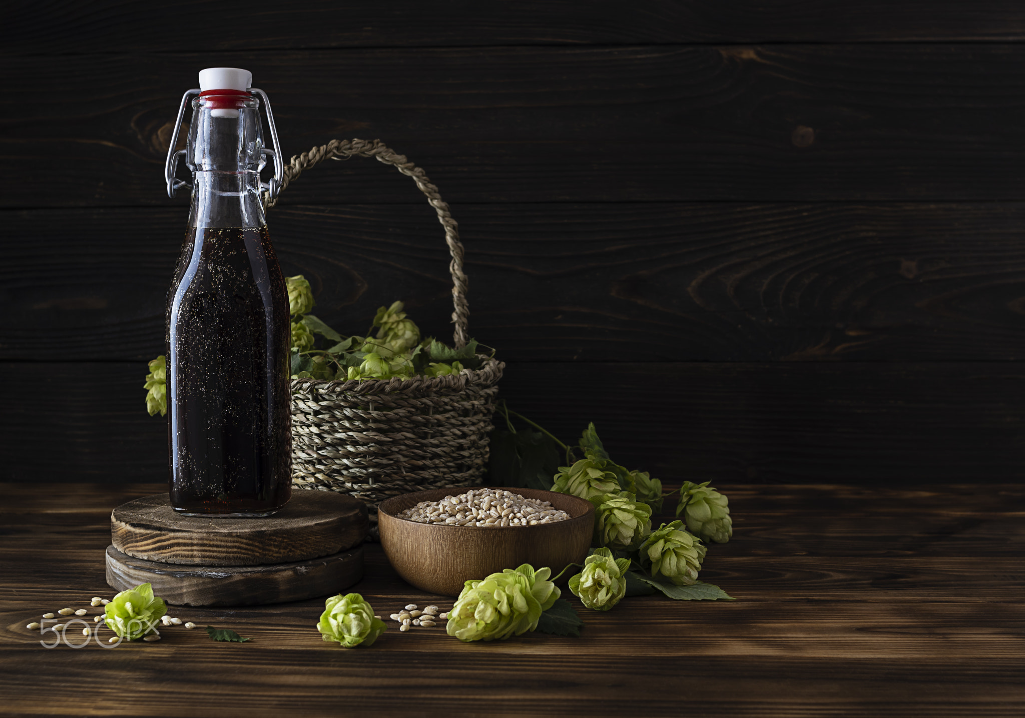 Dark beer in a transparent bottle on a wooden stand