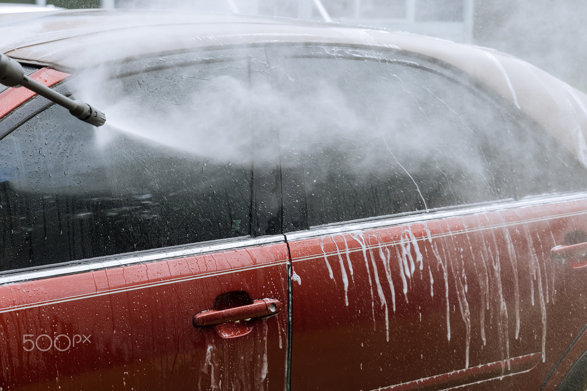 He washes his car under high pressure jet sprays with water while he