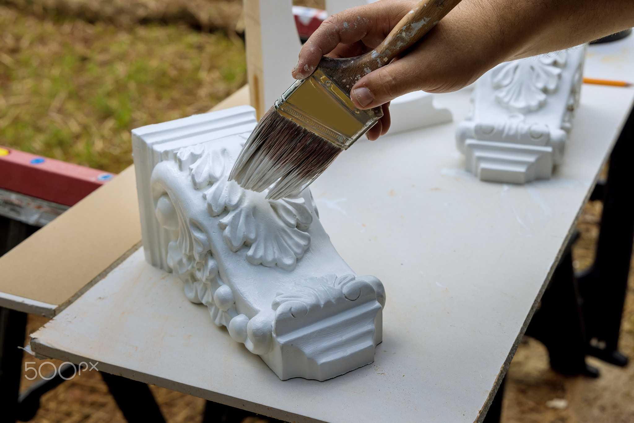 Painting wooden corbels for the kitchen island with worker is using