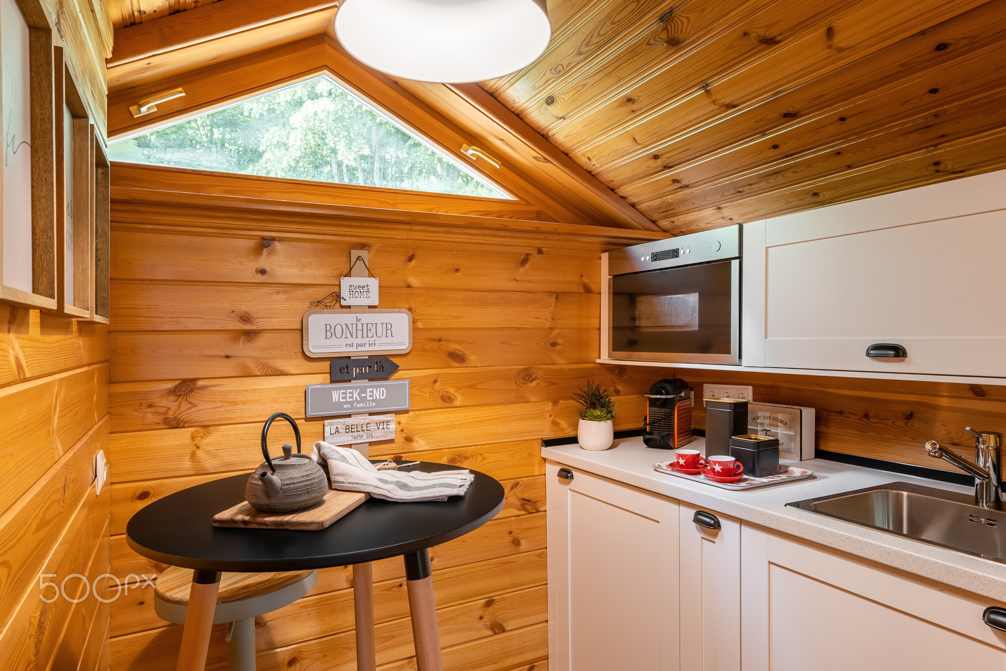 Compact kitchen with small round dining table in wooden house. Village