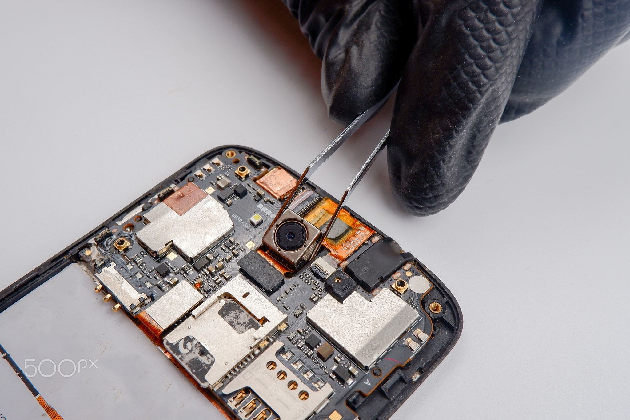 a smartphone repairman takes out a photo module from a smartphone with