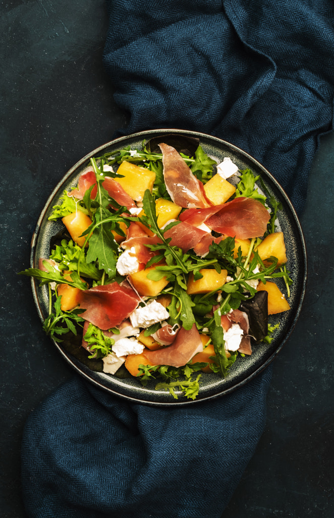 Fresh salad with cantaloupe melon, prosciutto, soft cheese and arugula by 5PH / 500px