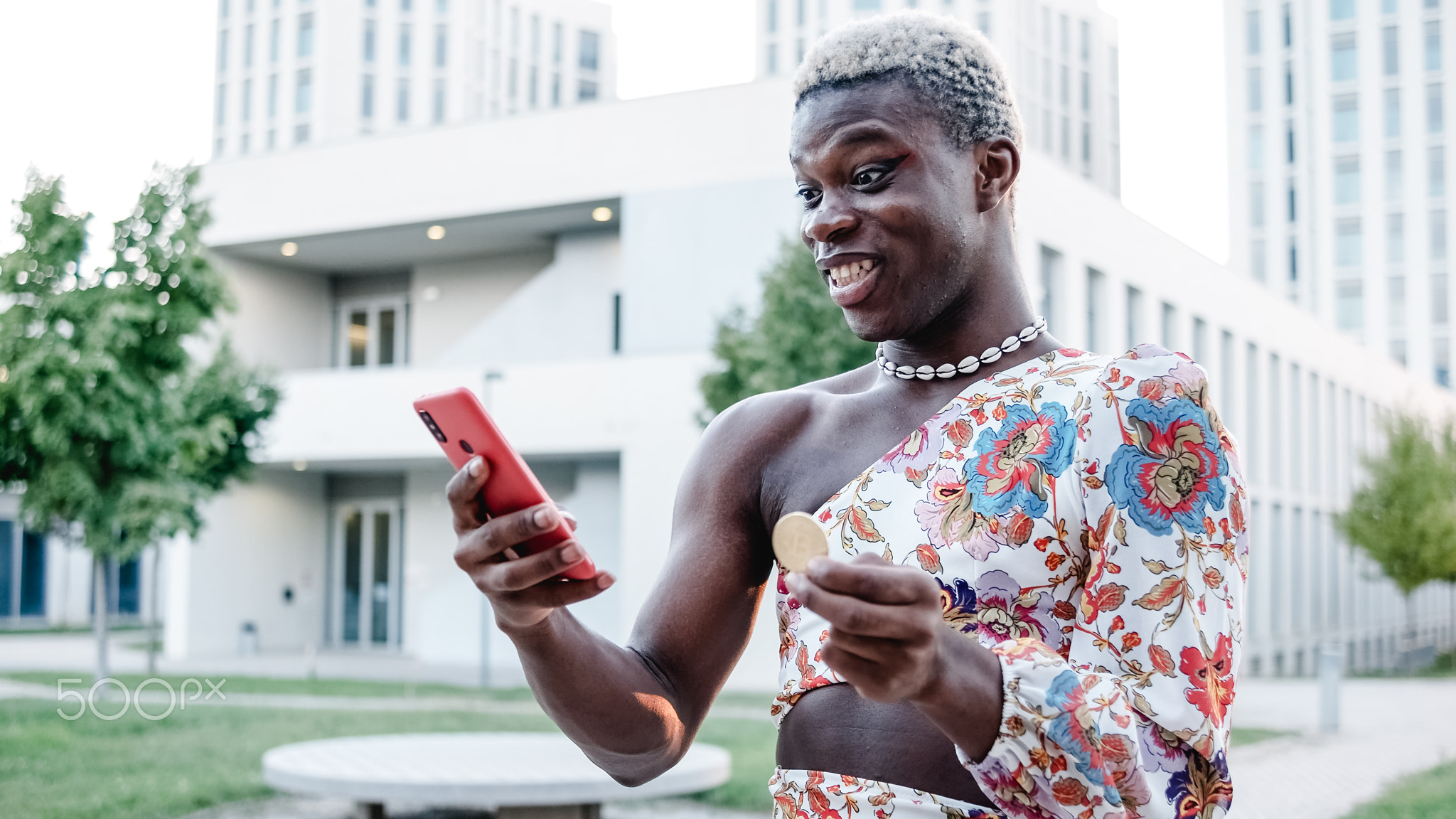 Black African transgender man with a bitcoin in his hand and a cell