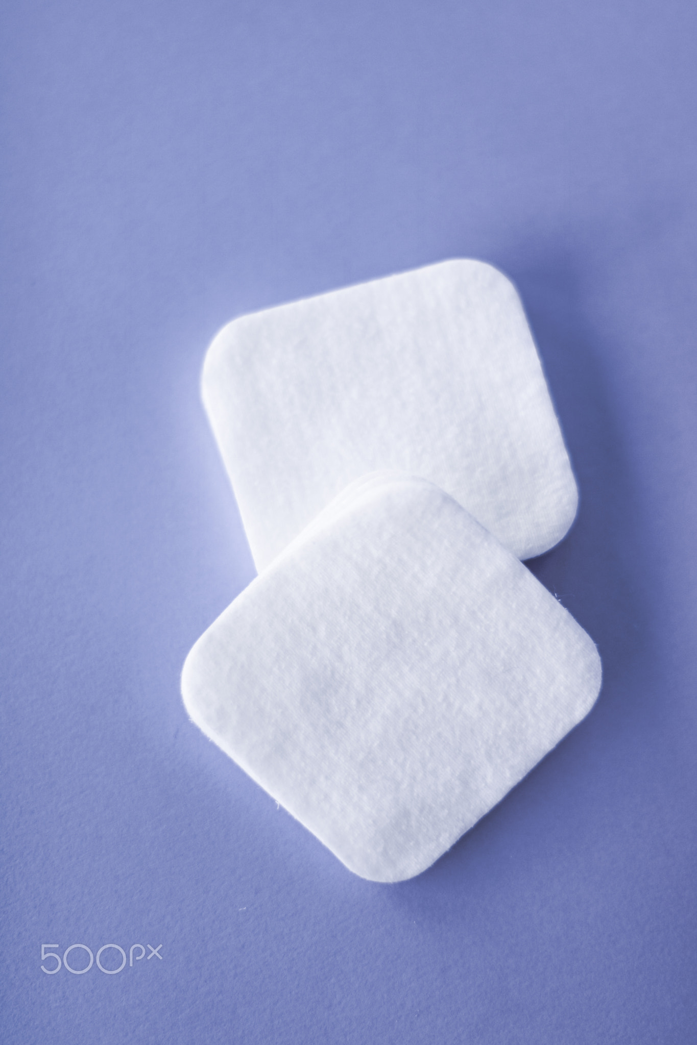 Organic cotton pads on purple background, cosmetics and make-up