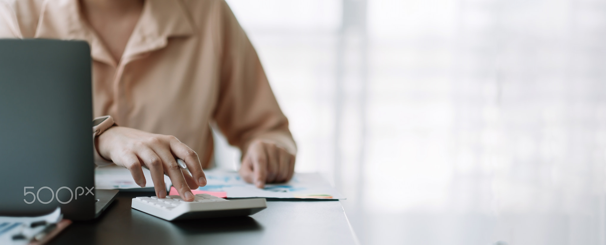 Business woman using calculator for do math finance on wooden desk in