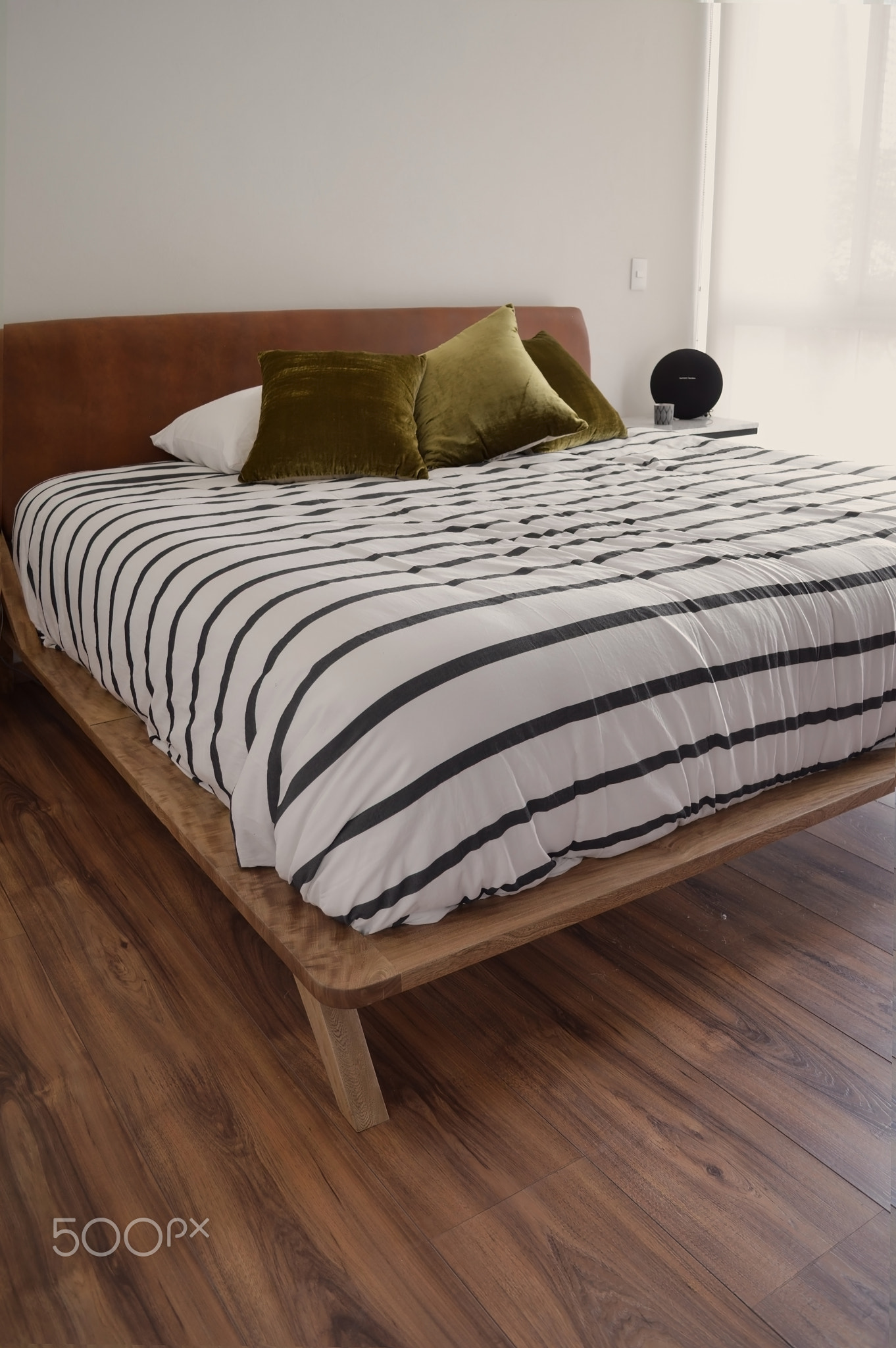 bed base, bedroom with mat on the floor, clay pot in the background, wooden credenza and mirror.